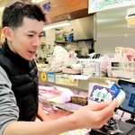 キャッシュレス決済ができるカードを端末にかざすセルバ名店会の北野良征さん＝神戸市東灘区森南町１