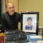 誠さんの遺影を持つ守さん。ランドセルや教科書、ノートは大切な宝物だ＝西宮市越水町