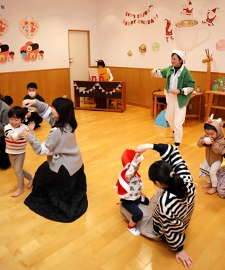 2024年12月に開いたイベント「英語でリトミック」で、音楽に合わせ体を動かす親子＝西宮市高松町、西宮阪急子育てコミュニティールーム