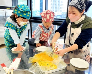 ポリ袋を使った調理でできた料理を取り分ける親子＝中央区文化センター
