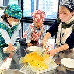 ポリ袋を使った調理でできた料理を取り分ける親子＝中央区文化センター