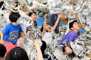 ちぎった新聞紙の「シャワー」に喜ぶ子どもたち＝コミスタこうべ