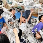 ちぎった新聞紙の「シャワー」に喜ぶ子どもたち＝コミスタこうべ