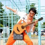 オレンジの衣装にギター片手でダンスや歌を披露する「須磨のスター」しんごお兄さん＝須磨区南町１、稲葉公園