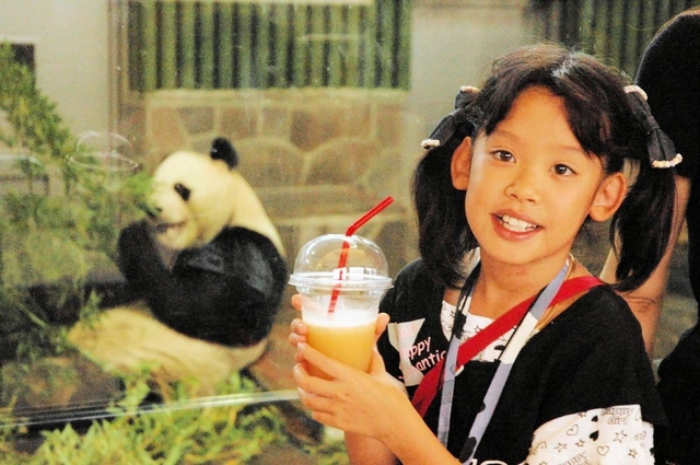 王子動物園名物「パンダと一緒・ミックスジュース」パンダのエサ、笹、リンゴ、ニンジンを素材にしたジュースを手に写真に収まる女の子＝２００４年９月、神戸市灘区、市立王子動物園