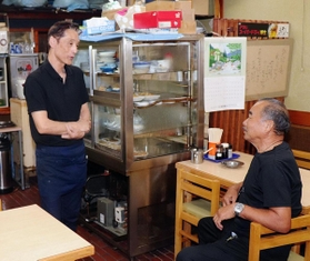 「食堂しろちゃん」の松岡泰司店主（左）と歓談する案内人の沢勝弘さん=神戸市垂水区塩屋町３