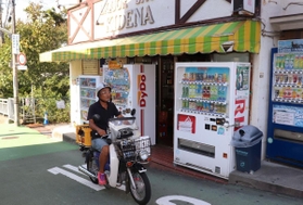 急勾配で狭い道をバイクで駆け抜ける貴伝名孝司さん＝神戸市垂水区塩屋町