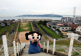 五色塚古墳に立つごしきまろ。背景には大阪湾が広がり、その先に淡路島が望める＝神戸市垂水区五色山４（撮影・三津山朋彦）