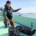 専用のかごで育ったシングルシードのカキと冨田虎太郎さん＝赤穂市沖