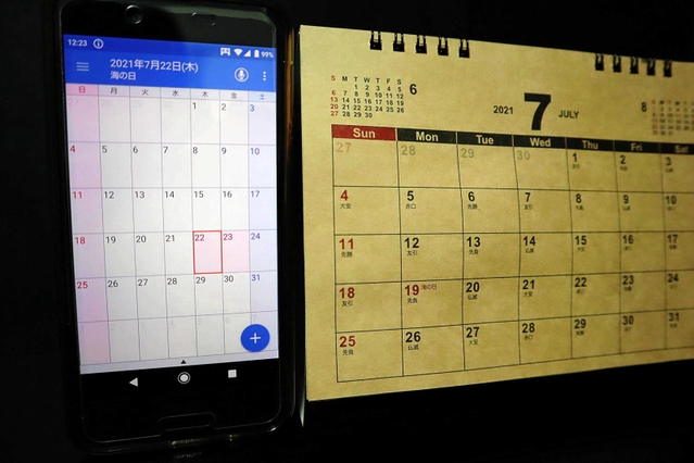 祝日の移動が急きょ決まったため、間に合わずに作製されたカレンダー（右）。スマホでは更新されて正しい日にちとなっている