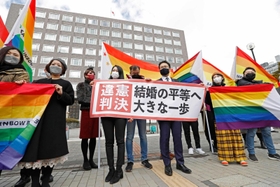 同性婚訴訟の札幌地裁判決後、「違憲判決」と書かれた紙を掲げる原告の弁護士と支援者ら＝３月１７日、札幌市
