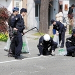 路上に散乱した乗用車の部品などを拾い集める警察官ら＝５日午後１時５５分、神戸市中央区割塚通６