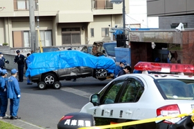 乗用車が衝突した●友会事務所の玄関付近を調べる兵庫県警の捜査員ら。衝突した乗用車はブルーシートに包まれ、レッカー移動された＝１１日午前８時３０分、淡路市志筑（注）●は「侠」の右が「夾」