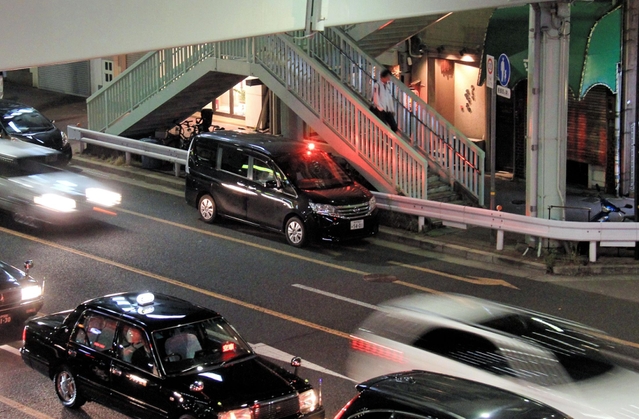 赤色灯をつけ、２４時間態勢で組事務所周辺を警戒する警察車両＝２７日夜、神戸市中央区