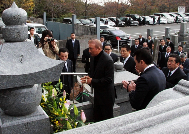 捜査員や報道関係者が集まる中、墓前で手を合わせる山口組の篠田建市組長ら＝１日午前１０時９分、神戸市灘区