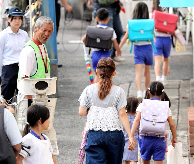 警察官らが見守る中、保護者と一緒に下校する児童ら＝１２日午後、神戸市長田区前原町１
