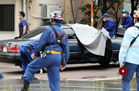 発砲事件があった現場を調べる捜査員ら。道路には血痕のようなものが見える＝１２日午前、神戸市長田区五番町