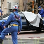 発砲事件があった現場を調べる捜査員ら。道路には血痕のようなものが見える＝１２日午前、神戸市長田区五番町