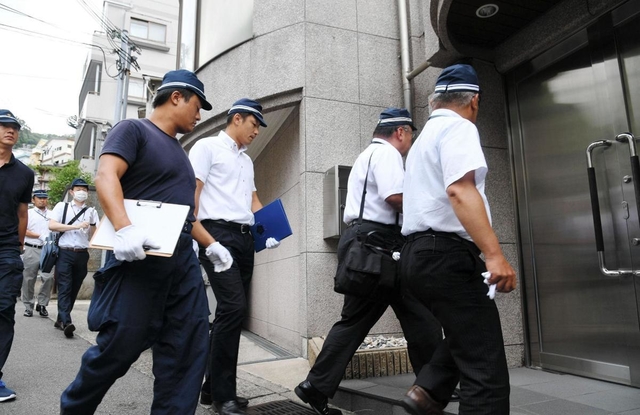 銃撃事件があった建物に入る兵庫県警の捜査員たち＝２２日午前、神戸市中央区熊内町９