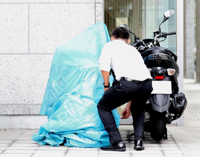 現場から約６００メートル南で見つかり、ブルーシートをかけられるバイク（中央）＝２３日午後、神戸市中央区内