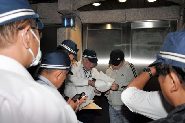 弘道会の拠点前で仮命令書を示す捜査員ら＝１１日午後９時３５分、神戸市中央区熊内町９