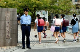現場に近い小学校前で児童の登校を見守る警察官＝１１日朝、神戸市中央区中山手通７厳戒の朝