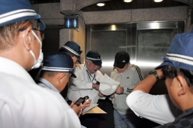 弘道会の拠点前で仮命令書を示す捜査員ら＝１１日午後９時３５分、神戸市中央区熊内町９