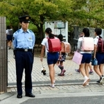 現場に近い小学校前で児童の登校を見守る警察官＝１１日朝、神戸市中央区中山手通７厳戒の朝