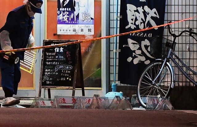 射殺現場を調べる捜査員。繁華街の一角で約３０発も撃ったとみられる＝１１月２７日夜、尼崎市神田南通１
